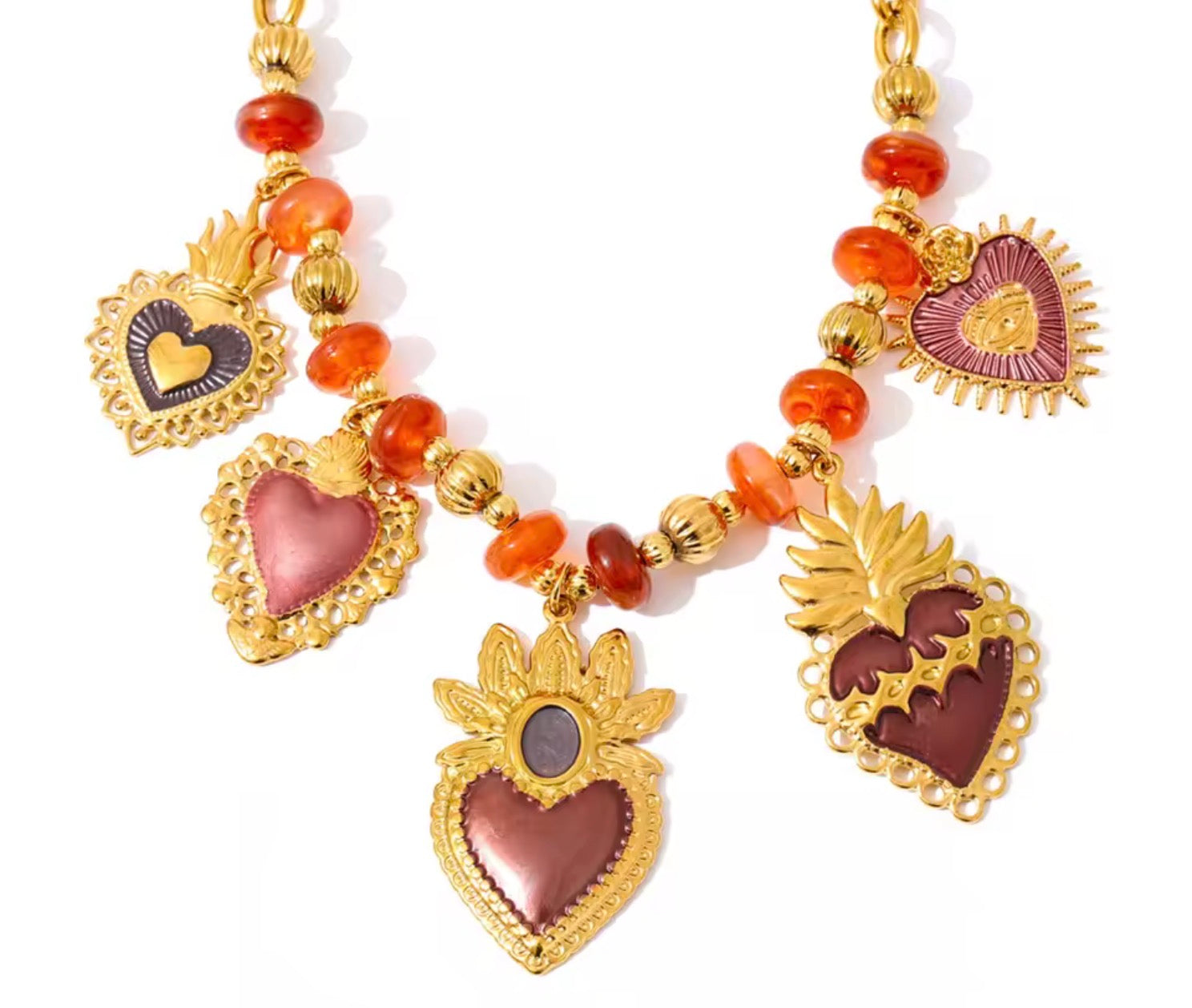 Collana con cuori sacri e dettagli smaltati.
Un gioiello ricco di simbolismo e carattere, che unisce il fascino dei cuori sacri a tonalità calde e avvolgenti. Le perline aranciate si alternano a dettagli dorati e pendenti smaltati, creando un mix vibrante e super distintivo