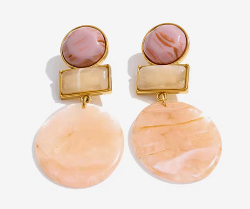 Orecchini pendenti effetto marmorizzato nei toni pastello.
Eleganti ma con un tocco creativo, questi orecchini uniscono forme geometriche e nuance calde per un risultato super raffinato. Le diverse texture effetto marmo creano profondità e movimento, perfette per illuminare il viso con delicatezza