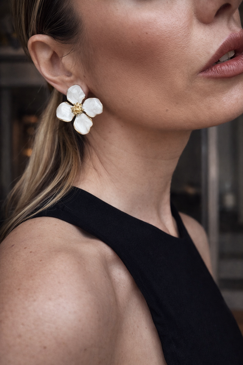 Orecchini a fiore smaltati.
Delicati ma d’impatto, questi orecchini a forma di fiore uniscono eleganza e freschezza. I petali bianchi effetto smalto, incorniciati da profili dorati, creano un contrasto luminoso e raffinato, perfetto per illuminare il viso