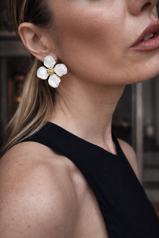 Orecchini a fiore smaltati.
Delicati ma d’impatto, questi orecchini a forma di fiore uniscono eleganza e freschezza. I petali bianchi effetto smalto, incorniciati da profili dorati, creano un contrasto luminoso e raffinato, perfetto per illuminare il viso