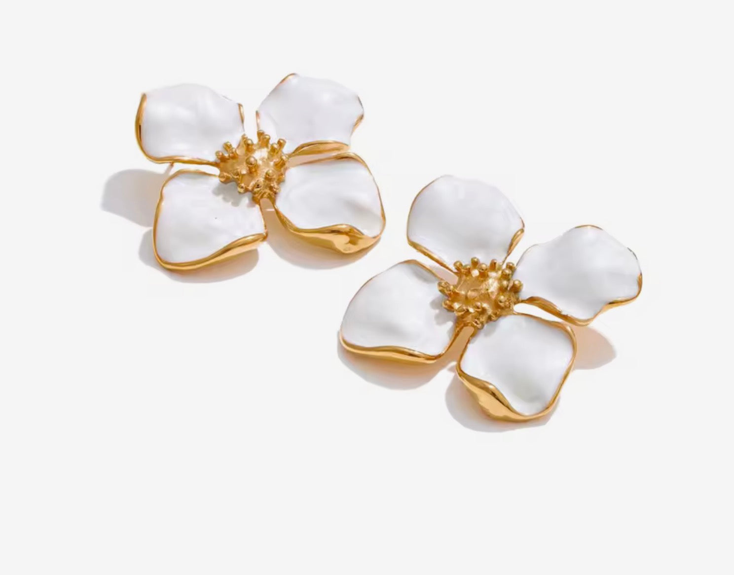Orecchini a fiore smaltati.
Delicati ma d’impatto, questi orecchini a forma di fiore uniscono eleganza e freschezza. I petali bianchi effetto smalto, incorniciati da profili dorati, creano un contrasto luminoso e raffinato, perfetto per illuminare il viso