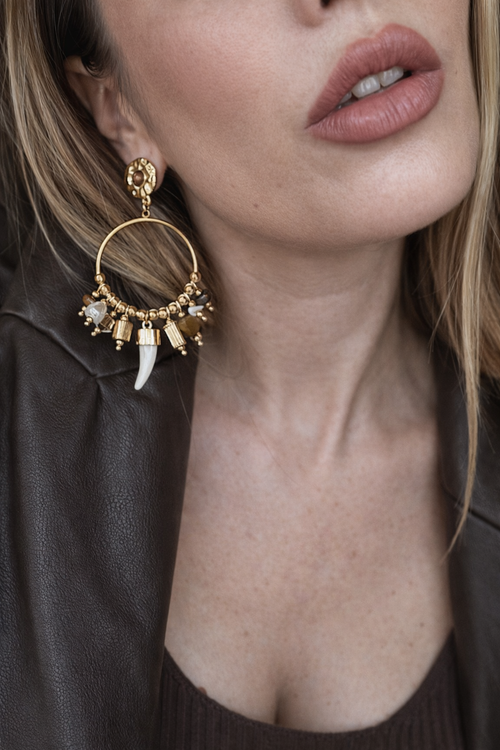 Orecchini a cerchio con charms e dettagli naturali.
Un modello ricco e super scenografico, pensato per chi ama accessori che fanno davvero la differenza. La struttura a cerchio è arricchita da piccoli charms e perline nelle tonalità calde, con un delicato pendente effetto corno che dona carattere e originalità.

Perfetti per dare movimento e personalità anche ai look più semplici, dal giorno alla sera